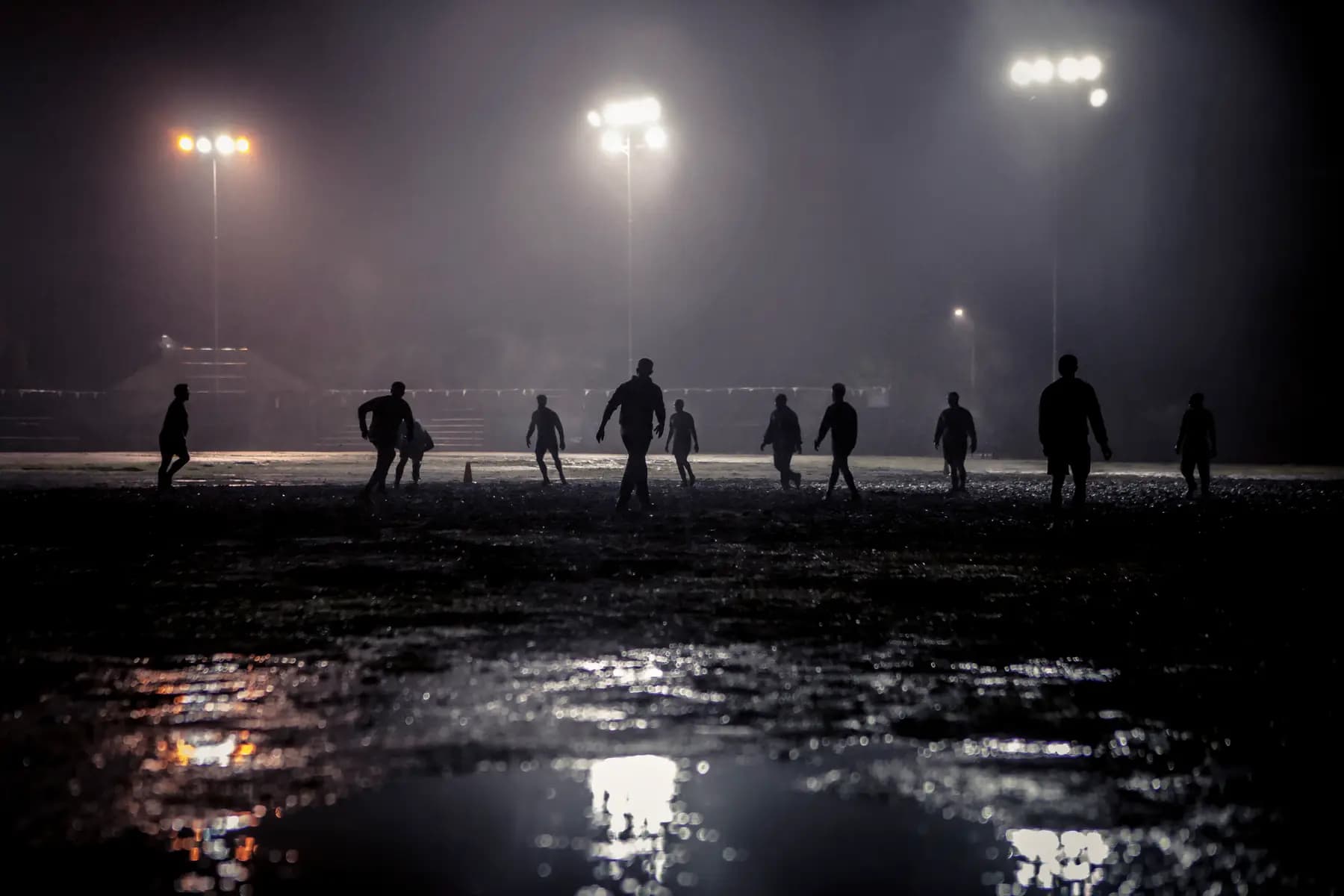 Fußballspieler im Flutlicht auf nassem Rasen bei Nacht