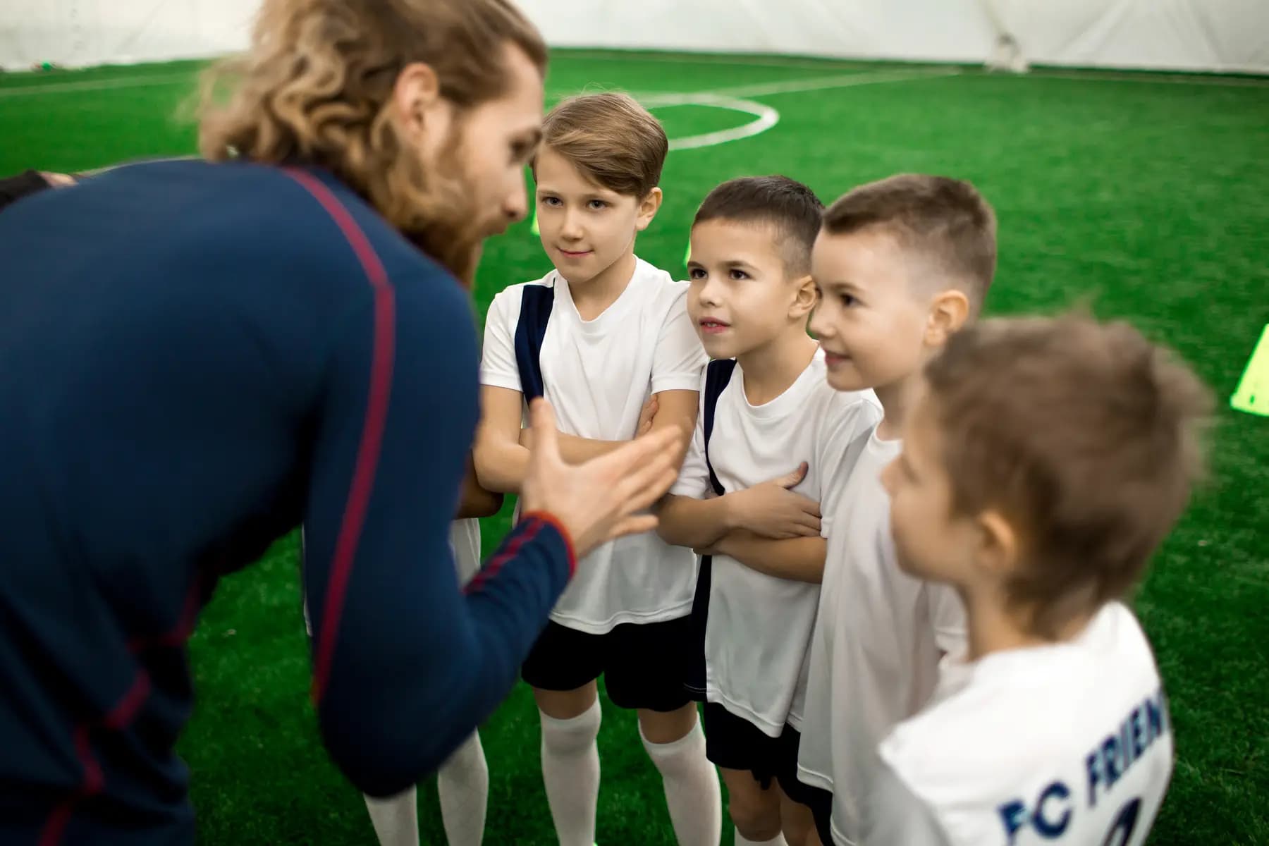 Trainer erklärt einer Gruppe junger Spieler eine Übung